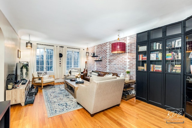 living room featuring brick wall and light hardwood / wood-style floors