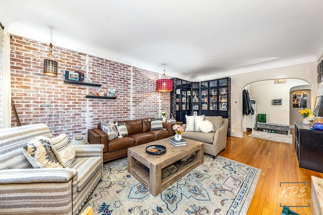 living room with light hardwood / wood-style flooring and brick wall