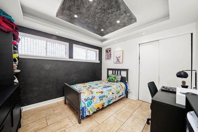 bedroom with a tray ceiling and a closet