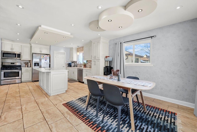 kitchen with a wealth of natural light, stainless steel appliances, white cabinets, and a kitchen island