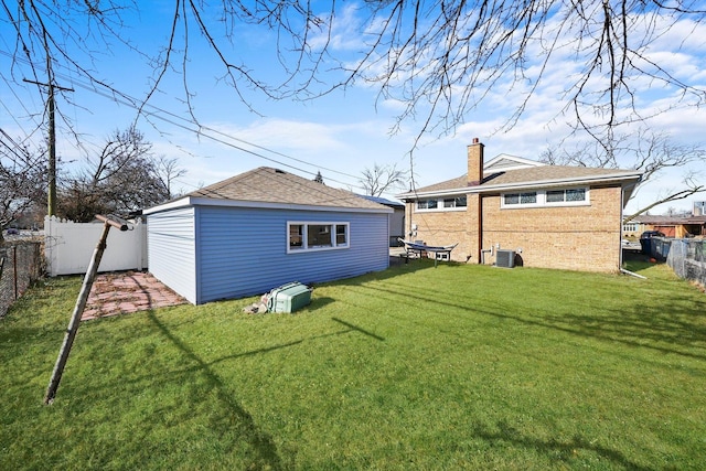 rear view of property with a lawn and central air condition unit