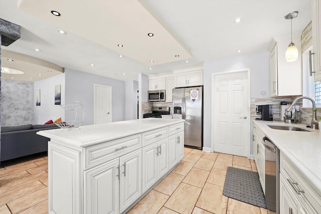 kitchen featuring sink, white cabinetry, backsplash, stainless steel appliances, and decorative light fixtures