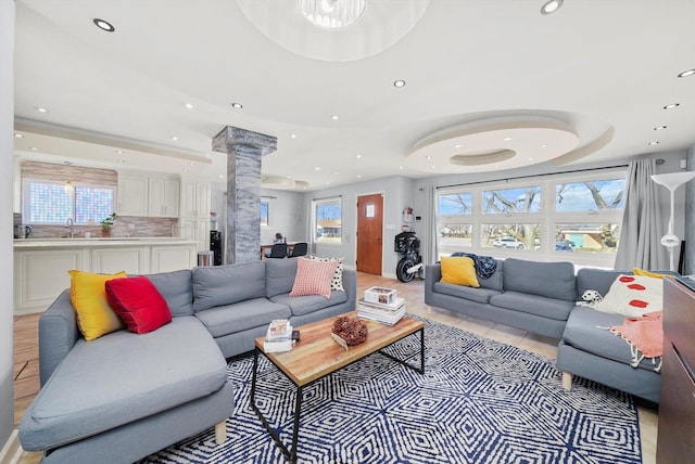 living room featuring ornate columns, sink, and light tile patterned floors