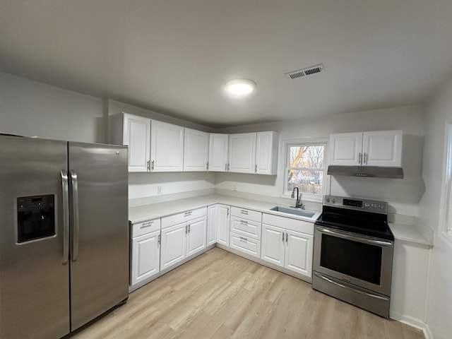 kitchen with appliances with stainless steel finishes, sink, white cabinets, and light hardwood / wood-style floors