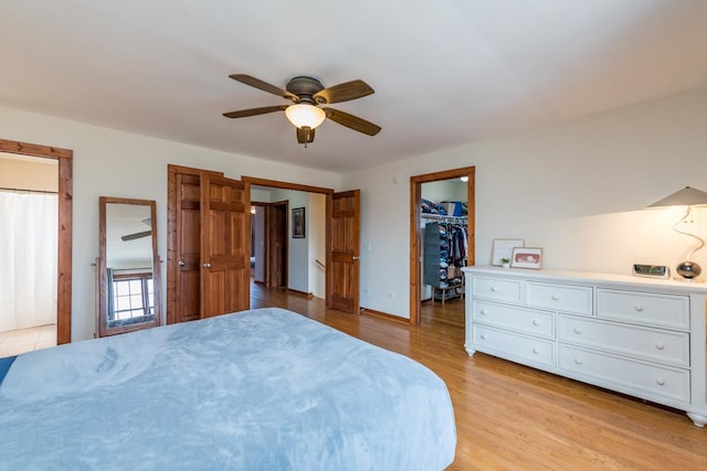 bedroom with ceiling fan, a spacious closet, a closet, and light hardwood / wood-style flooring