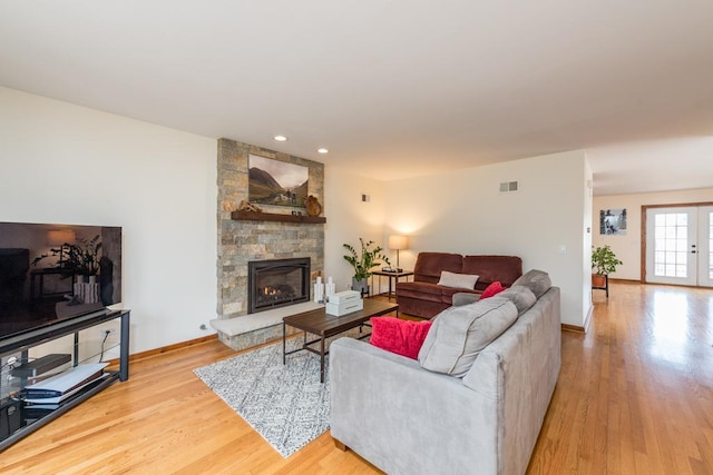 living room with a fireplace, french doors, and light wood-type flooring