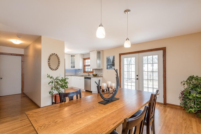 dining room with sink, light wood-type flooring, and french doors