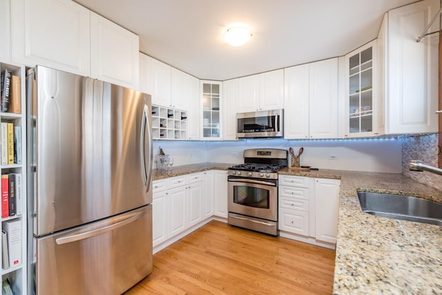 kitchen featuring light stone counters, stainless steel appliances, sink, and white cabinets