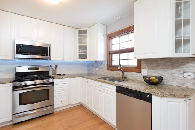 kitchen with white cabinetry, sink, light stone counters, and stainless steel appliances