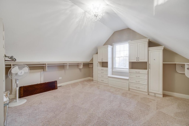 spacious closet featuring lofted ceiling, light carpet, and an inviting chandelier