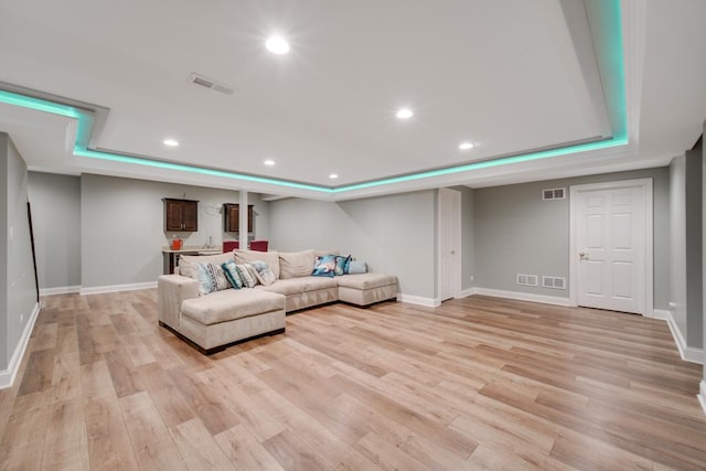 living room featuring a tray ceiling and light hardwood / wood-style flooring