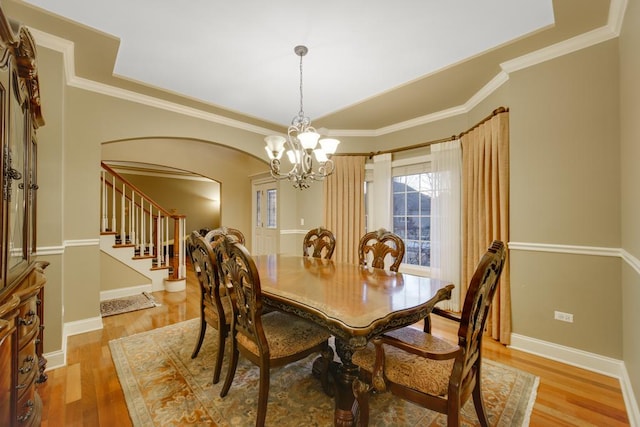 dining area featuring ornamental molding, an inviting chandelier, and light wood-type flooring