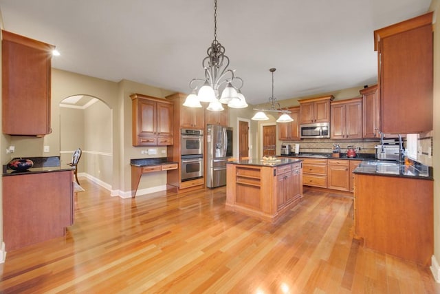 kitchen with stainless steel appliances, decorative light fixtures, light hardwood / wood-style floors, and a kitchen island