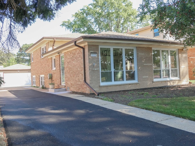 view of home's exterior with brick siding, a garage, entry steps, and an outdoor structure