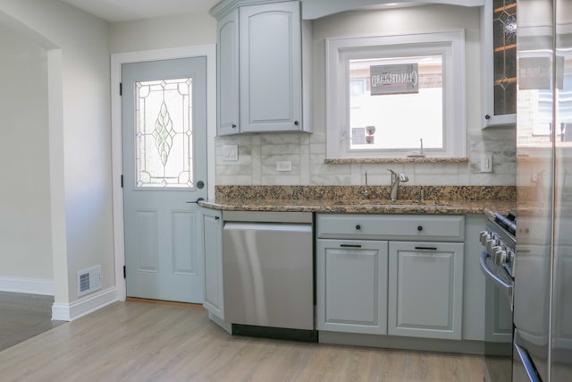 kitchen with decorative backsplash, light wood-style flooring, stainless steel appliances, and a sink