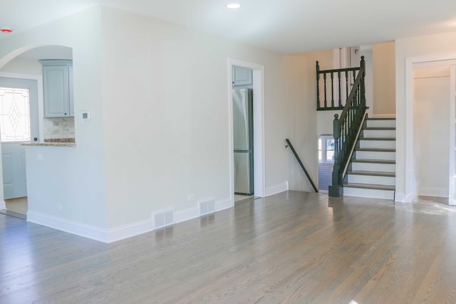 unfurnished living room featuring visible vents, baseboards, and wood finished floors