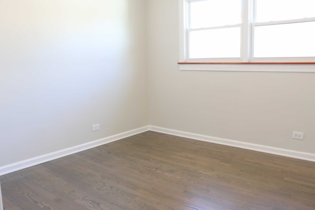 spare room featuring dark wood-type flooring and baseboards