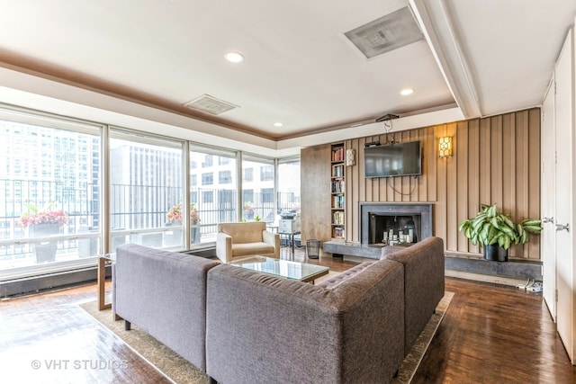 living room featuring hardwood / wood-style floors, wooden walls, and a raised ceiling