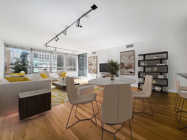 dining room with wood-type flooring and rail lighting