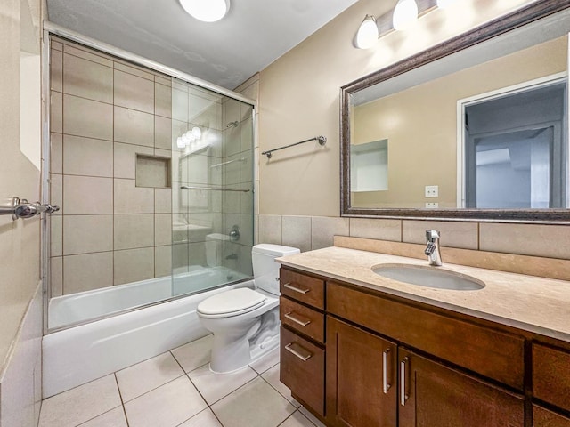 full bathroom with tile walls, backsplash, tile patterned flooring, enclosed tub / shower combo, and vanity