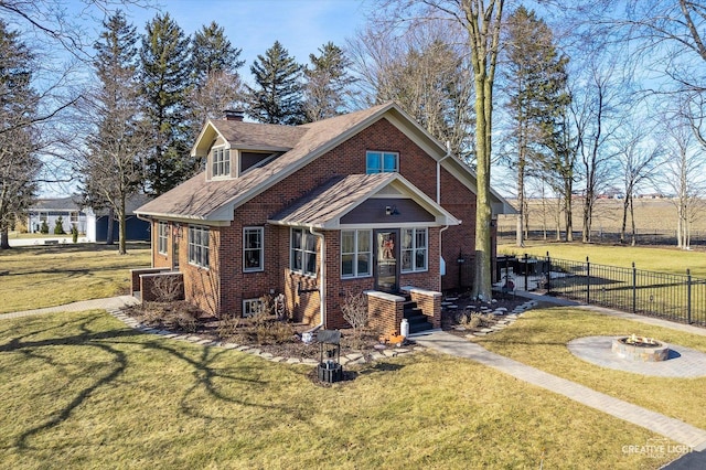 view of front of house featuring brick siding, a chimney, an outdoor fire pit, fence, and a front lawn