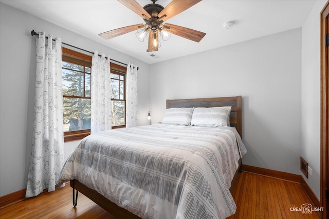 bedroom featuring visible vents, ceiling fan, baseboards, and wood finished floors