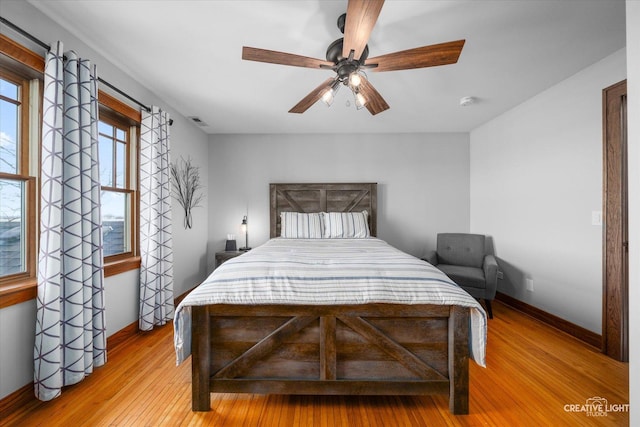 bedroom with a ceiling fan, light wood-type flooring, visible vents, and baseboards