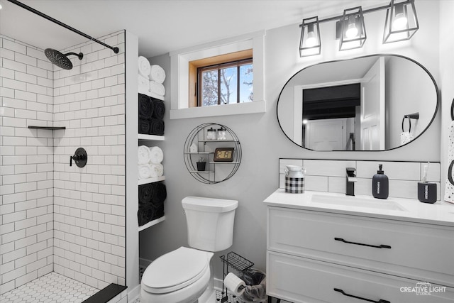 full bath with vanity, a tile shower, toilet, and decorative backsplash