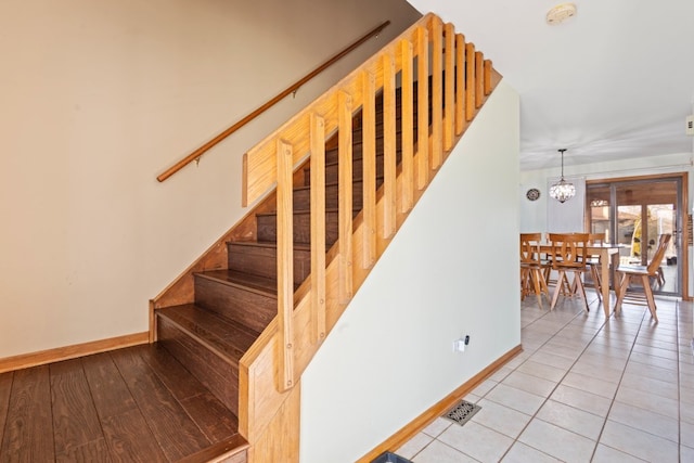 stairs with an inviting chandelier and tile patterned flooring