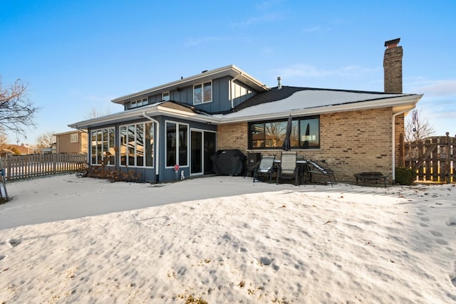 snow covered house with a patio area and a sunroom