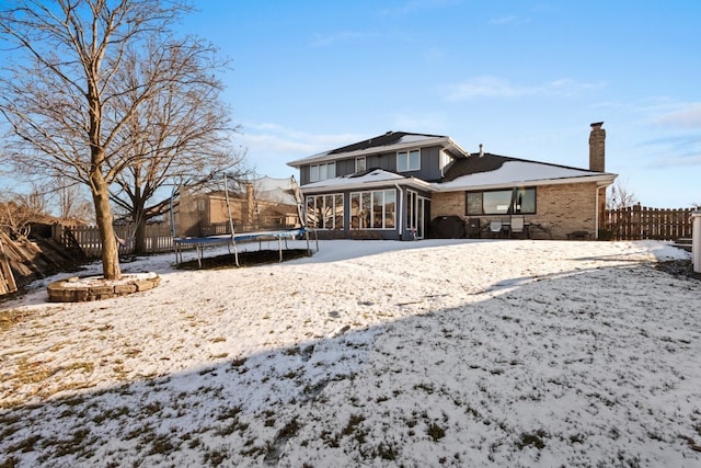 snow covered rear of property featuring a trampoline