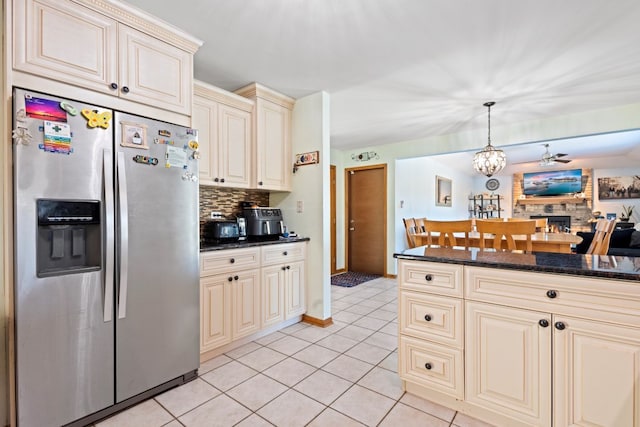 kitchen with light tile patterned flooring, decorative light fixtures, stainless steel fridge with ice dispenser, dark stone countertops, and cream cabinets