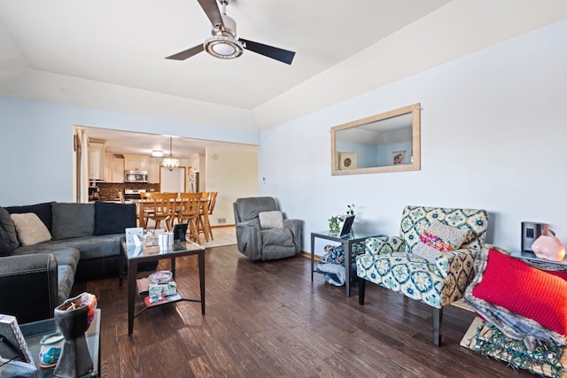 living room with dark wood-type flooring, lofted ceiling, a tray ceiling, and ceiling fan with notable chandelier