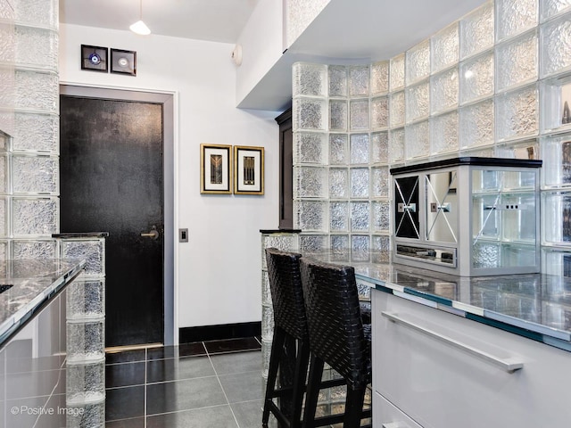 kitchen with dark tile patterned floors and a towering ceiling