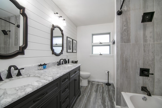 full bathroom featuring vanity, toilet, tiled shower / bath combo, and hardwood / wood-style floors