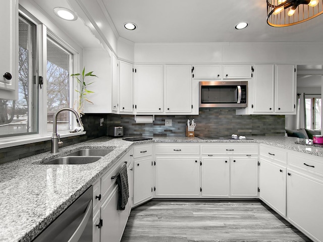 kitchen featuring sink, appliances with stainless steel finishes, backsplash, light stone countertops, and white cabinets