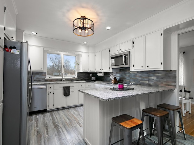 kitchen featuring stainless steel appliances, white cabinets, a kitchen breakfast bar, and kitchen peninsula