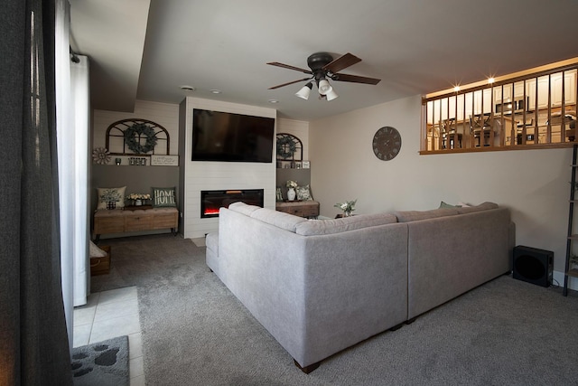 carpeted living room featuring a large fireplace and ceiling fan