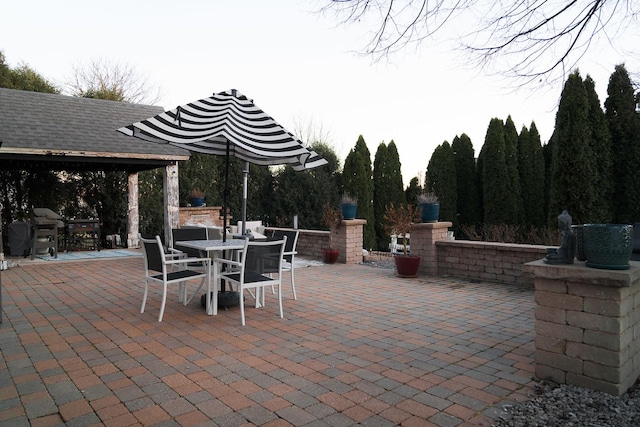 view of patio / terrace with an outdoor brick fireplace, a grill, and a gazebo