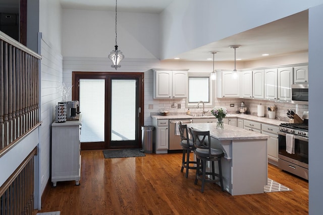 kitchen with appliances with stainless steel finishes, decorative light fixtures, a kitchen island, and white cabinets