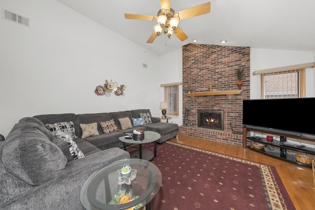 living room featuring ceiling fan, lofted ceiling, a fireplace, and wood-type flooring