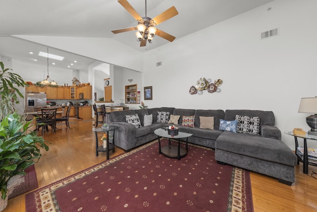 living room with ceiling fan, high vaulted ceiling, and light hardwood / wood-style floors