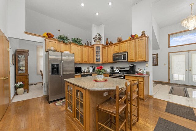 kitchen featuring a breakfast bar area, high vaulted ceiling, stainless steel appliances, a center island, and french doors