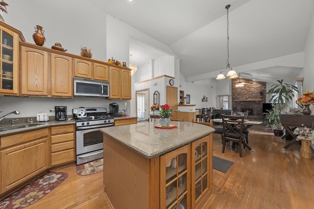 kitchen with sink, decorative light fixtures, a center island, a brick fireplace, and stainless steel appliances