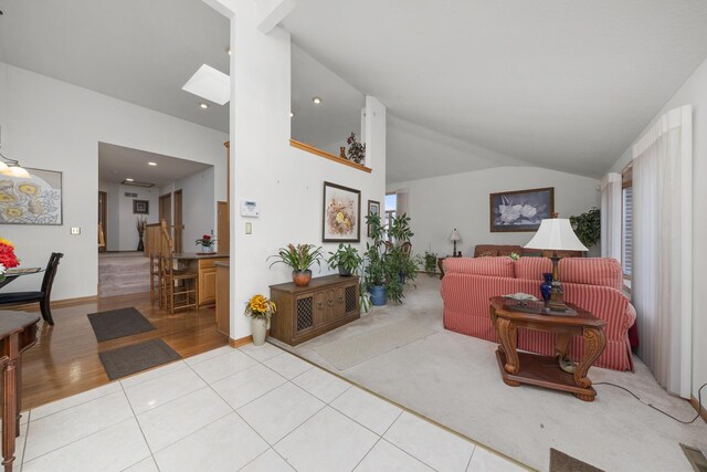 living room featuring light tile patterned floors, a skylight, and high vaulted ceiling