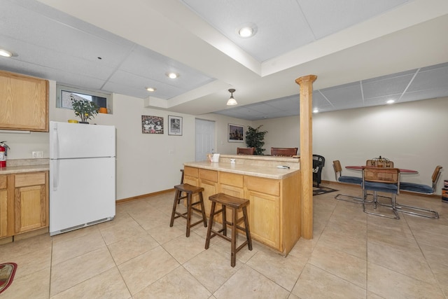 kitchen featuring light tile patterned floors, a paneled ceiling, a breakfast bar, and white refrigerator