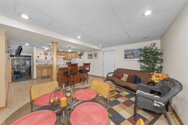 tiled living room featuring a drop ceiling and bar area