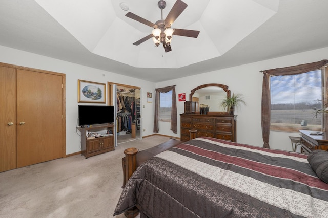 carpeted bedroom with ceiling fan, a raised ceiling, and multiple windows