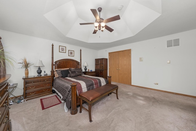 carpeted bedroom featuring a tray ceiling and ceiling fan