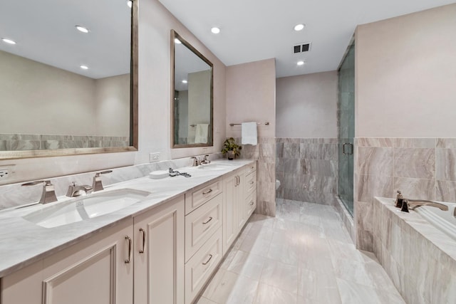 bathroom featuring vanity, shower with separate bathtub, and tile walls